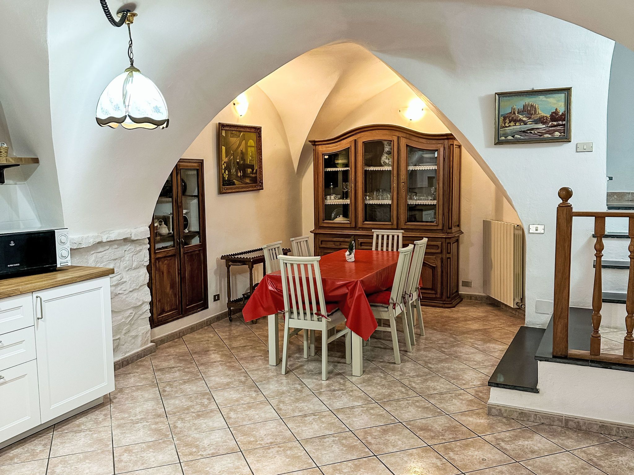 Un comedor con una mesa dispuesta para cuatro, un aparador de madera y un cuadro en la pared.