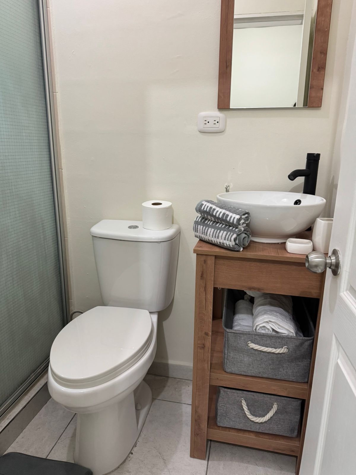 A small bathroom with a toilet, a sink, and a mirror.