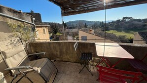 Eine Terrasse mit Tisch und Stühlen, Blick auf ein Dorf und einen klaren Himmel.