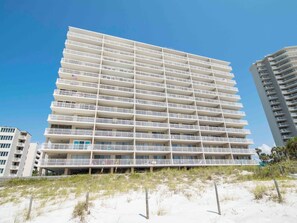 A multi-story hotel with balconies, located near a sandy beach. - Dunes of Panama #B501 | Gulf Front + Amenities (Panama City Beach)