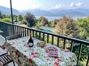 A balcony with a table set for a meal, overlooking a mountainous landscape and a body of water. - "Casa Bella Vista" by Interhome (Stresa)