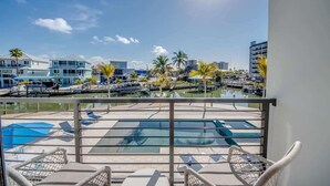 Uma varanda com vista para uma marina, uma piscina e uma fileira de edifícios.