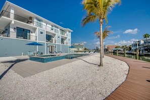 A modern hotel with a pool, outdoor seating, and a waterfront view. - 501 Palermo 6 Master Suites with Private Balconies (Fort Myers Beach)