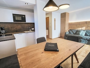 A modern kitchen with a microwave, a coffee machine, and a wooden dining table with a book. - Wohnung "Meran" by Interhome (Gargazon (Gargazzone))
