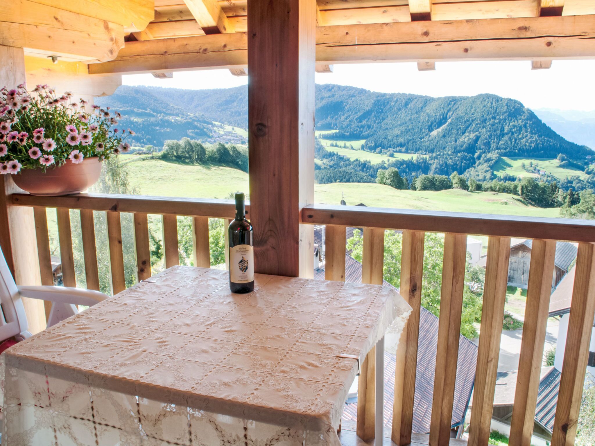 A wooden balcony with a table, a bottle, and a potted plant.