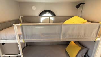 A bunk bed with a window above and a lamp to the right.