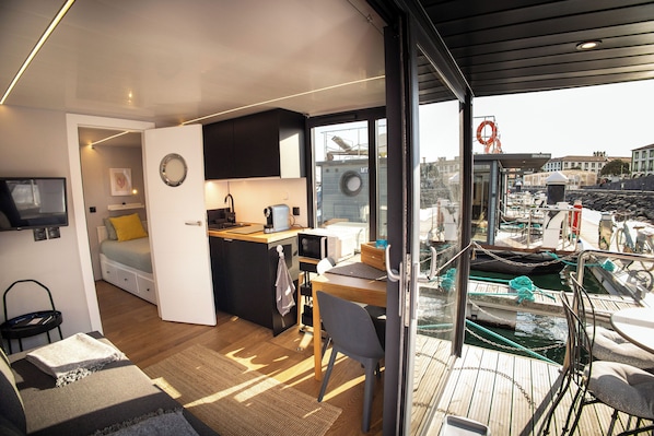 Un interior compacto y moderno con kitchenette, una zona de comedor y vistas al puerto deportivo.