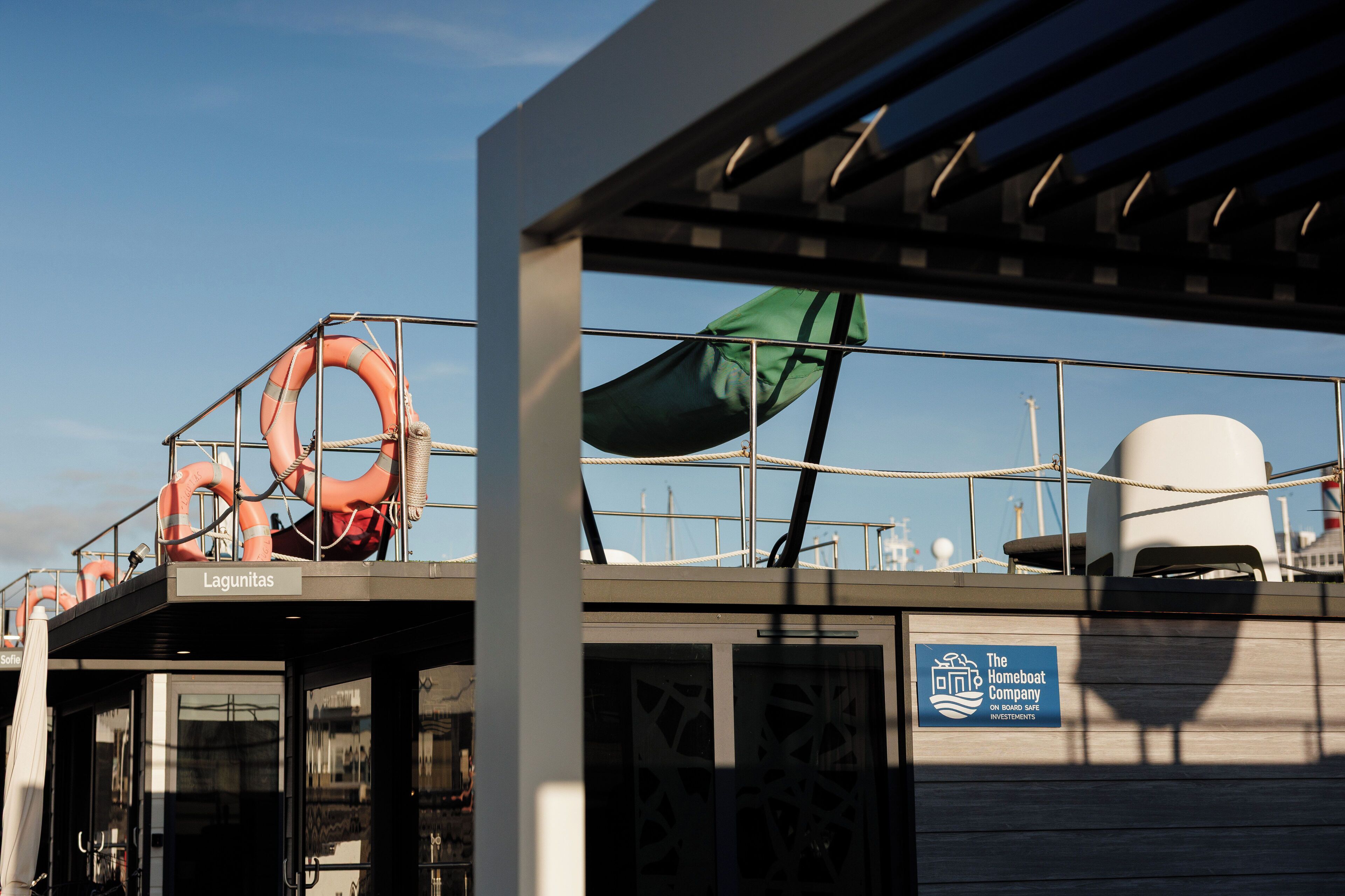 Une plateforme avec des bouées de sauvetage, un drapeau vert et un panneau indiquant « The Homeboat Company ».