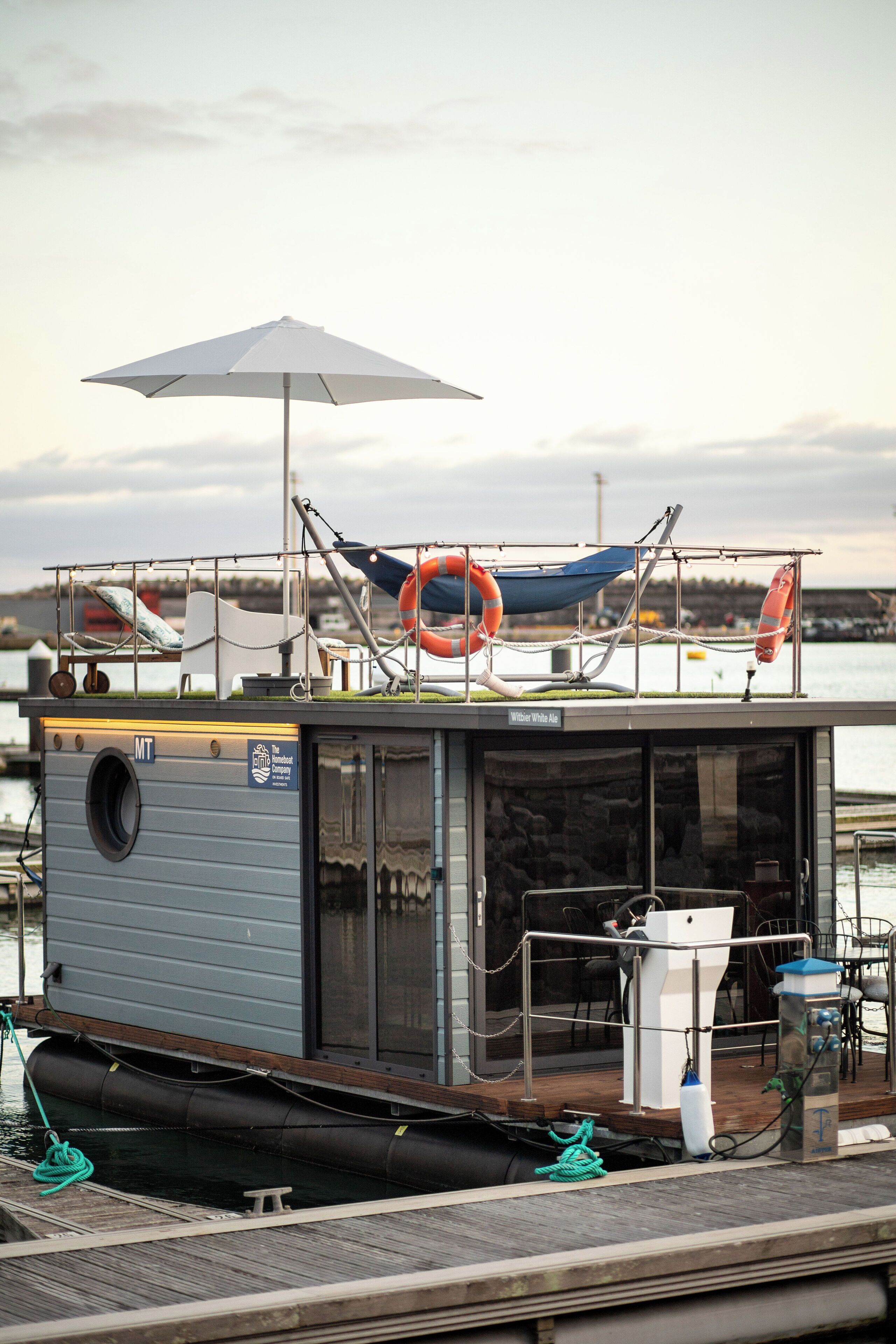 Een kleine, moderne boot met een afdak, een reddingsboei en een witte parasol.