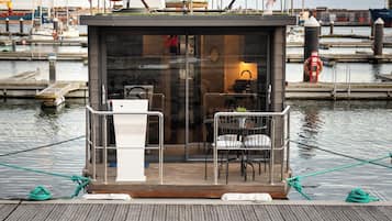 A small, enclosed dock area with a table and chairs, a hammock, and life rings.