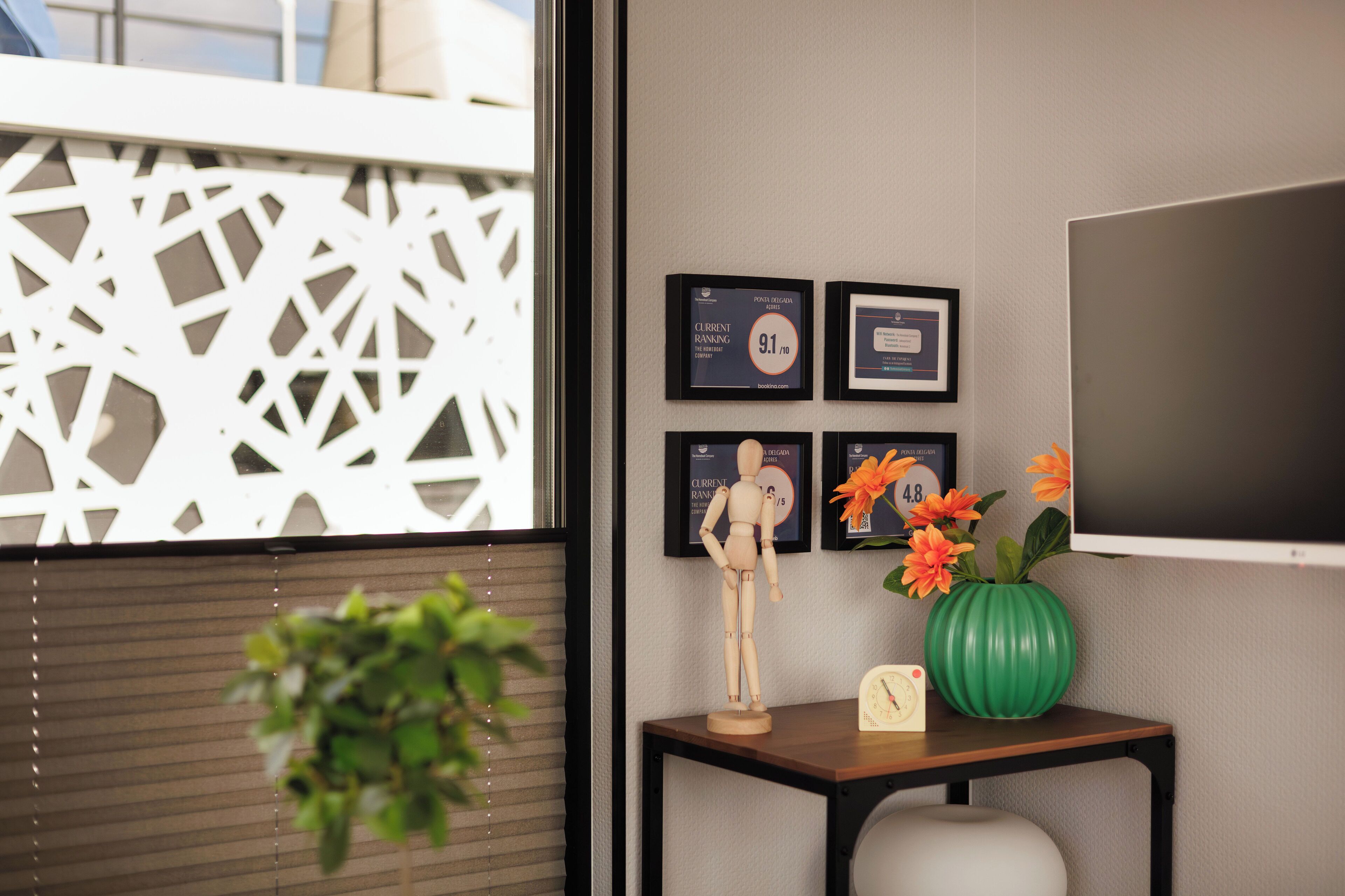 A room with a wooden mannequin, a green vase with flowers, and framed certificates on the wall.
