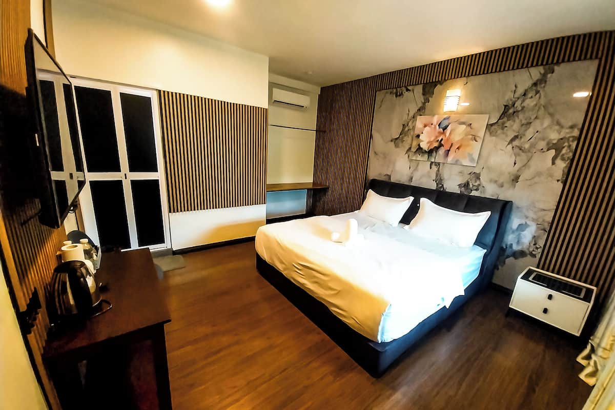 A modern hotel room with a large bed, a desk with a chair, a wardrobe, and a bathroom.