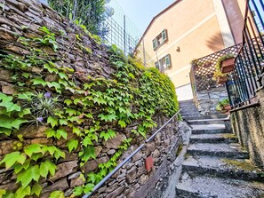 A stone staircase with a metal handrail, surrounded by greenery and a building with a yellow facade. - Ein Garten auf Camogli von Holiday World by Interhome (Camogli)