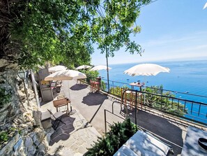 A terrace with outdoor seating, a stone wall, and a view of the sea. - Ein Garten auf Camogli von Holiday World by Interhome (Camogli)