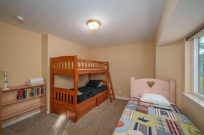 Une chambre d’enfant avec des lits superposés, une bibliothèque et une fenêtre.