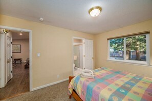 Un dormitorio con una cama, una ventana y una puerta que da a otra habitación.