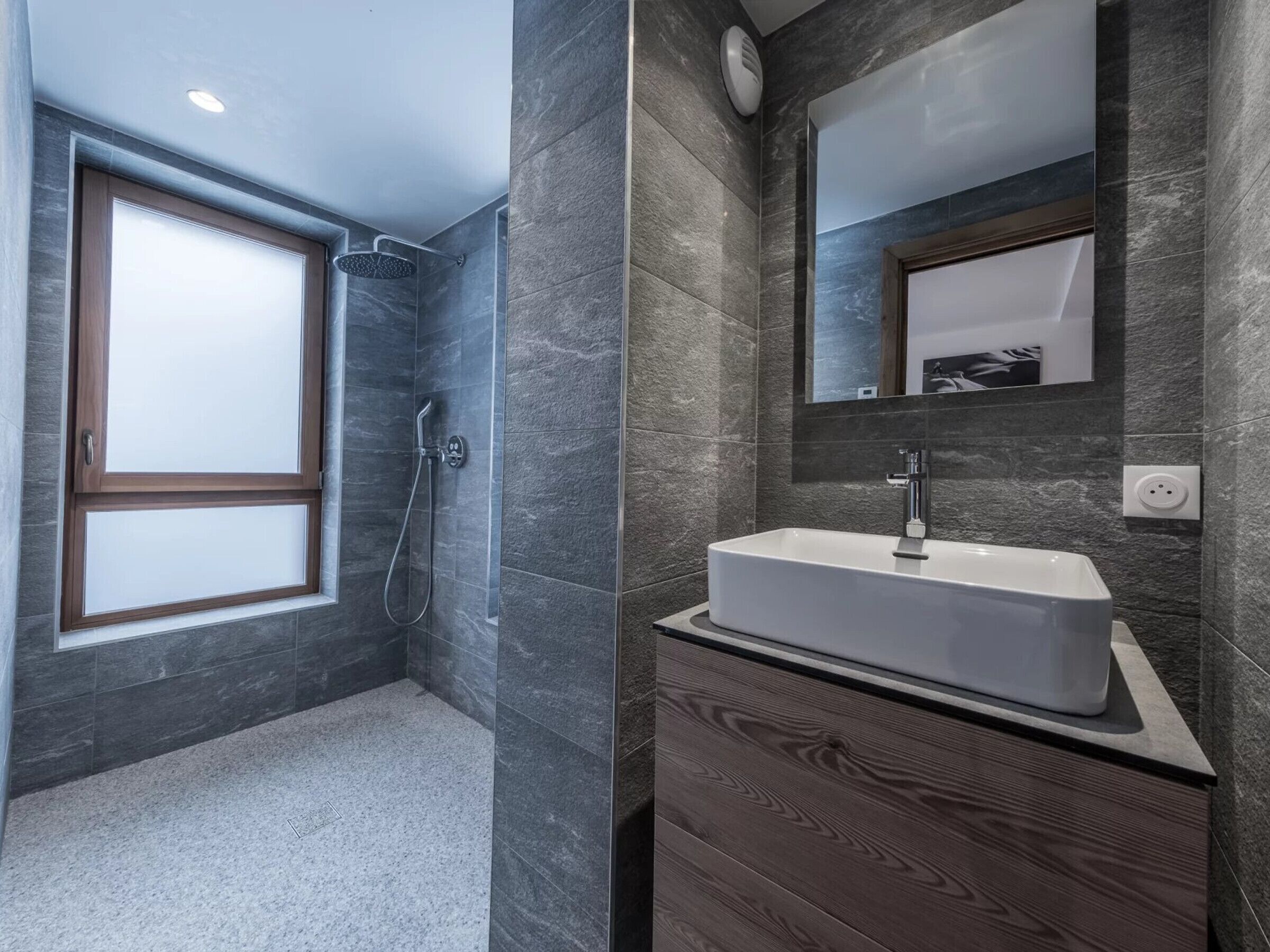Un bagno moderno con doccia a filo pavimento, uno specchio grande e un lavabo integrato.