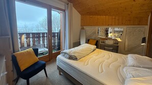 A bedroom with a large bed, a chair, a desk, and a view of the outdoors. - THOLLON - 6 pers, 70 m2 (Thollon-les-Mémises)