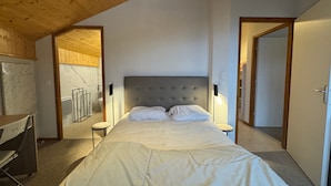 A bedroom with a large bed, wooden ceiling, and a view of a bathroom. - THOLLON - 6 pers, 70 m2 (Thollon-les-Mémises)