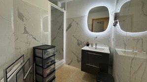 A bathroom with marble walls, a vanity with a mirror, and a black storage unit. - THOLLON - 6 pers, 70 m2 (Thollon-les-Mémises)