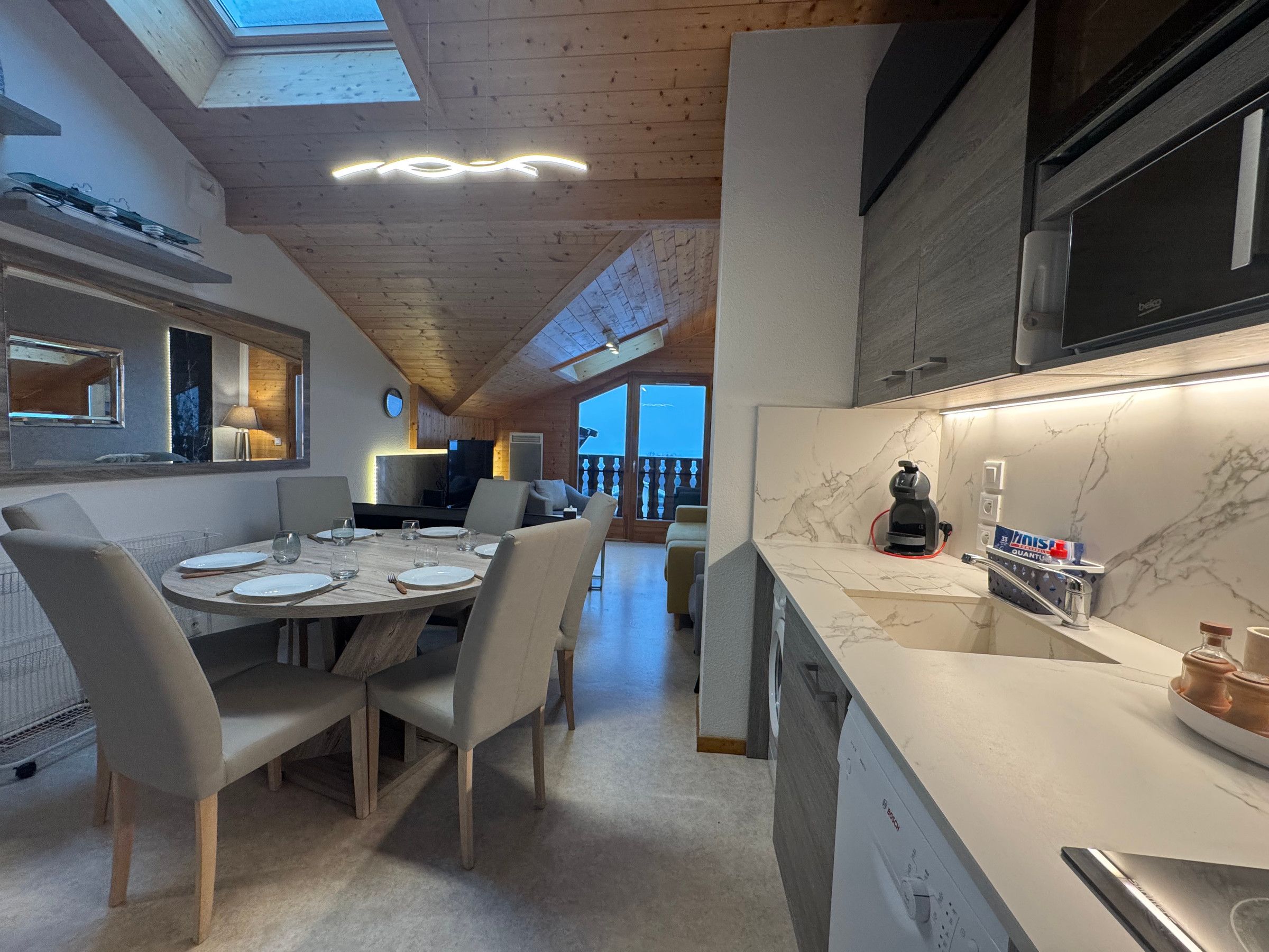 Cozinha moderna com máquina de lavar louça Bosch, bancada de mármore e vista para o exterior.