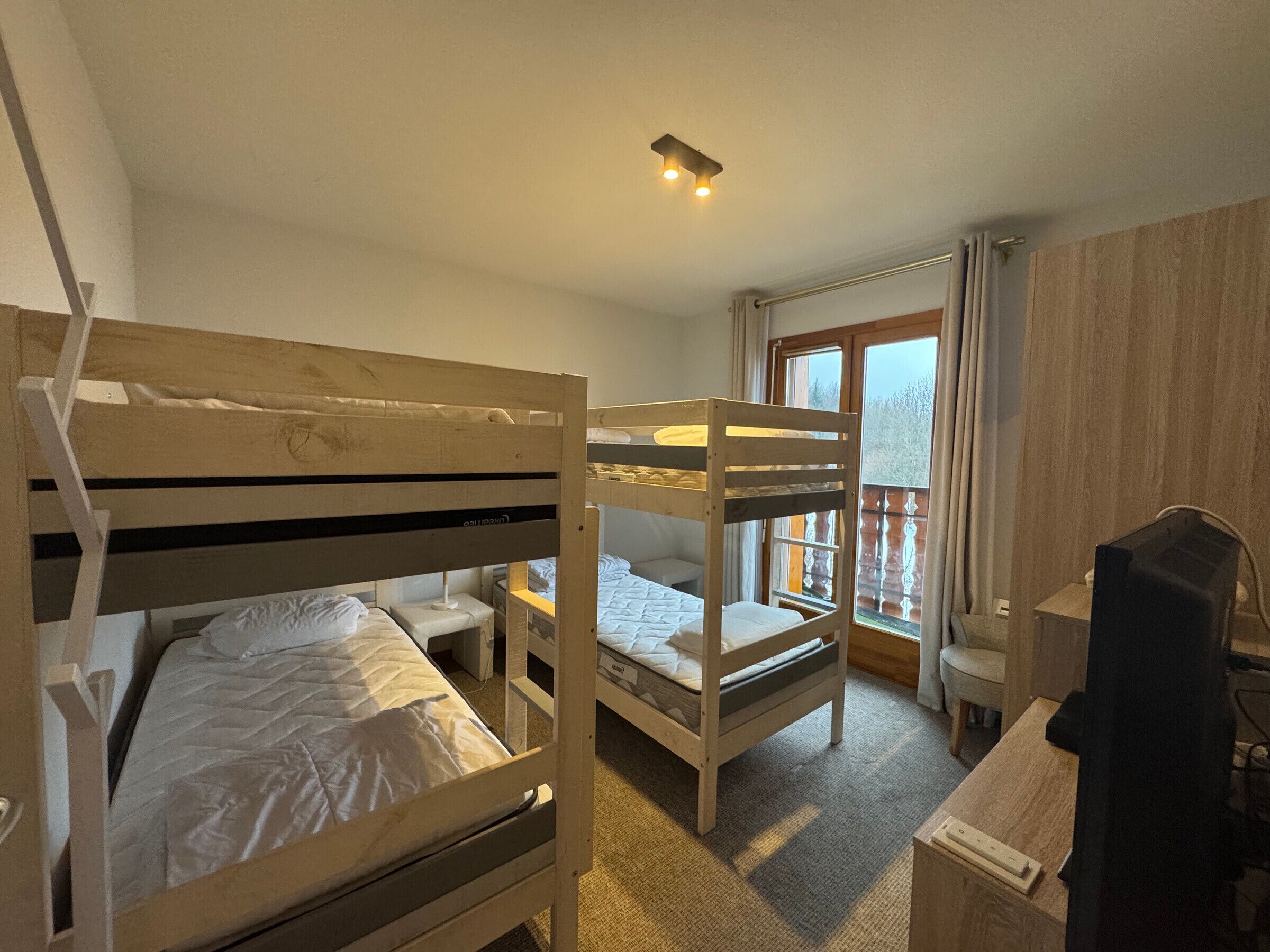A room with bunk beds, a desk, and a window with curtains.