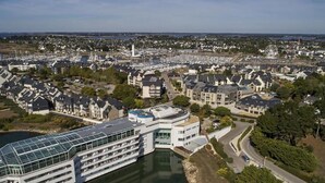 Un hôtel situé au bord de l’eau, avec plusieurs étages, une façade en verre et un quai.