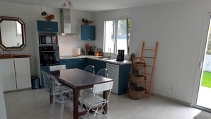 Une cuisine moderne avec un coin repas, comprenant un îlot central, un four à micro-ondes, une cuisinière et un évier.