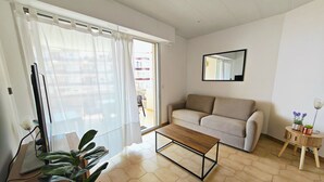 A living room with a sofa, a coffee table, a TV, and a potted plant. - Renovated Studio - 5 Pers - Sea View - Canet-en-Roussillon (Canet-en-Roussillon)