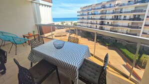 A balcony with a table and chairs, overlooking a beach and a multi-story building. - Renovated Studio - 5 Pers - Sea View - Canet-en-Roussillon (Canet-en-Roussillon)
