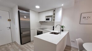 Eine moderne Küche mit weißen Schränken, einem Edelstahlkühlschrank, einer Mikrowelle und einem Spülbecken.