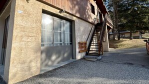 A building with a wooden exterior, a garage door, and a staircase leading to a second floor. - Charming 3-Room Apartment, Sleeps 4 in La Salle-les-Alpes (La Salle-les-Alpes)