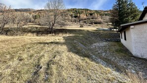 A rural landscape with a house, a clear sky, and a hilly background. - Charming 3-Room Apartment, Sleeps 4 in La Salle-les-Alpes (La Salle-les-Alpes)