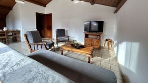A cozy living room with a wooden ceiling, a sofa, two armchairs, a coffee table, a TV, and a fireplace. - Charming 3-Room Apartment, Sleeps 4 in La Salle-les-Alpes (La Salle-les-Alpes)