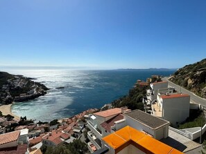 A coastal town with buildings along the seaside, a clear view of the ocean, and a hilly landscape in the background. - Charming 2-bedroom apartment with terrace and parking in Roses (Roses)