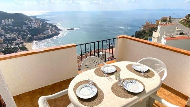 A balcony with a table set for two, overlooking a coastal view. - Charming 2-bedroom apartment with terrace and parking in Roses (Roses)