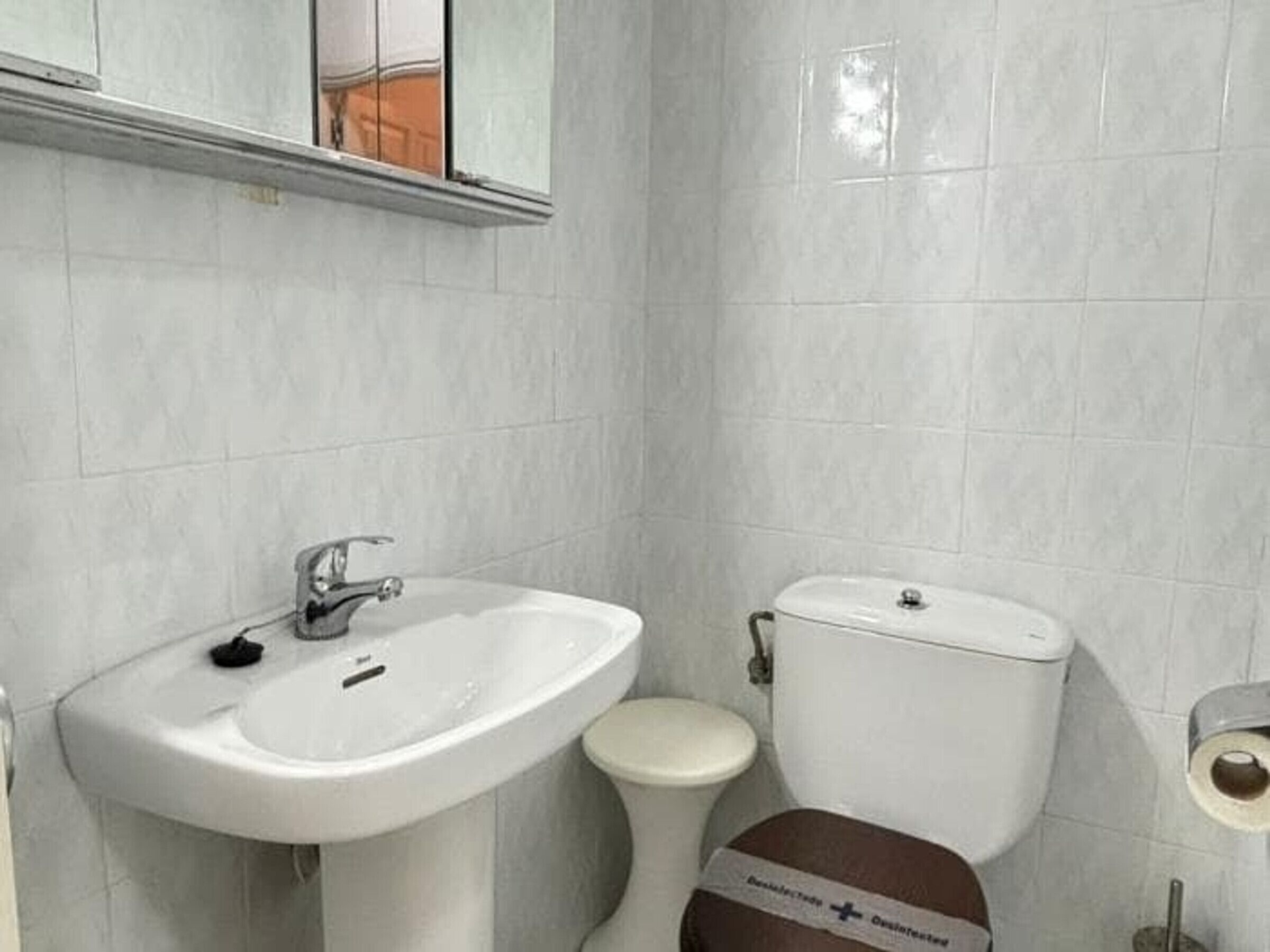 Une salle de bain avec un lavabo blanc, des toilettes et un miroir au-dessus du lavabo.