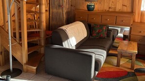 A cozy wooden interior with a sofa, a lamp, and a staircase. - Charming Chalet for 5 Guests in Châtel (Châtel)