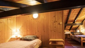 A cozy attic bedroom with wooden walls, a single bed, a small bench, and a nightstand with a lamp. - Charming Chalet for 5 Guests in Châtel (Châtel)