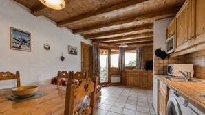 A wooden interior with a dining table, chairs, a washing machine, and a kitchen area. - Cozy apartment near Cernix with balcony and parking (Crest-Voland)