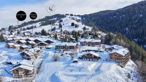 A snow-covered mountain village with wooden chalets and a ski slope. - Cozy apartment near Cernix with balcony and parking (Crest-Voland)