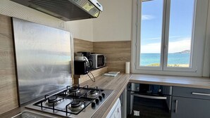 Eine moderne Küche mit Gasherd, Mikrowelle und Meerblick durch ein Fenster.