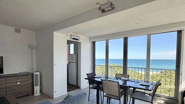 Eine moderne Wohnung mit Essbereich, einer Küche und einem Balkon mit Meerblick.