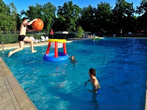 Une piscine dotée d’une structure de jeux aquatiques, d’une terrasse carrelée et d’une clôture.
