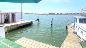 A dock with a boat, a covered area with equipment, and a clear view of the water and distant shoreline. - Semi-detached house 5 bedrooms in Roses, near center with terrace and canal (Roses)