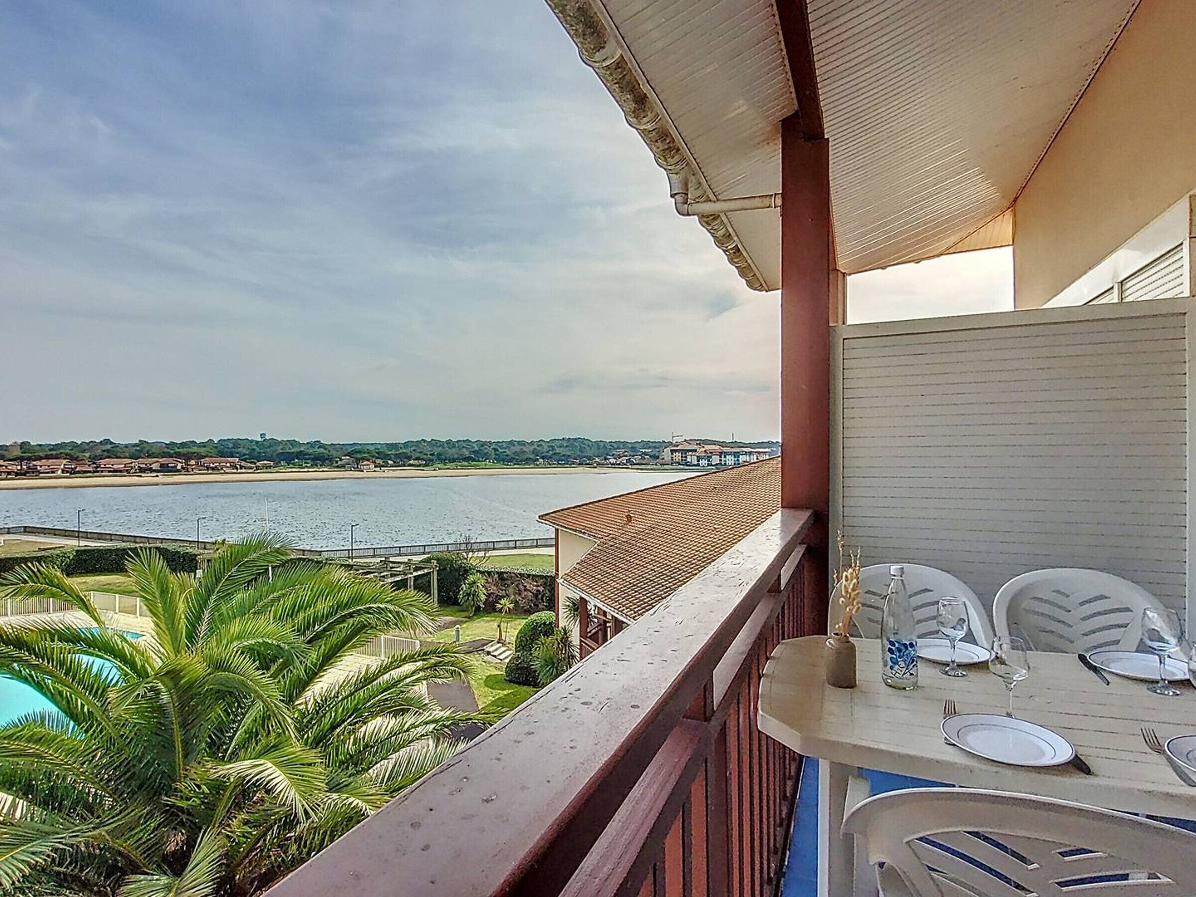 Een balkon met uitzicht op een strand en een zwembad.