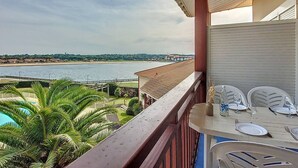 Un balcón con vista a la playa y una piscina.