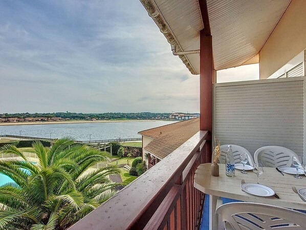 A balcony with a view of a beach and a pool.