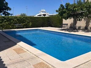 Ein rechteckiger Swimmingpool mit glasklarer blauer Wasseroberfläche, umgeben von einer Steindeck.