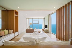 Una camera d'albergo moderna con un ampio letto, un'area salotto e vista sull'oceano.